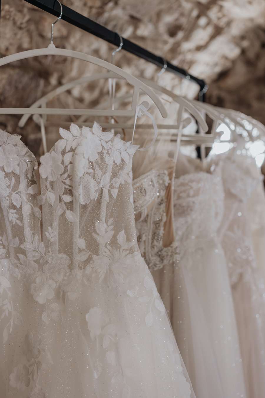 Nahaufnahme von edlen Brautkleidern mit floraler Spitze und Glitzerdetails bei Novia Feliz Brautmode in Heppenheim und Weinheim