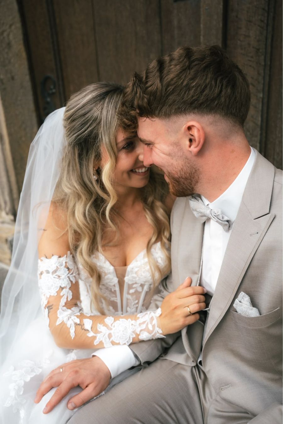 Braut mit Brautstyling und Schleier lacht mit Bräutigam – Novia Feliz Brautstyling Heppenheim